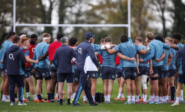 A large group of England Rugby Men A players, coaches and support staff huddle during a training session at the University of Bath.