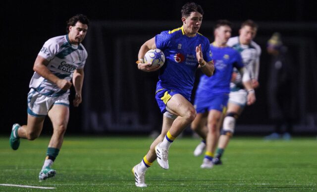 University of Bath rugby player Sam Winters running, with ball in hand, as Swansea defenders, in white, are left behind him