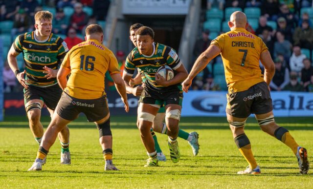 Aiden Ainsworth-Cave, with ball in hand, runs at two Newcastle defenders during his PREM Rugby debut for Northampton Saints.