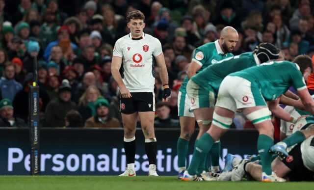 Wales player Louie Hennessey, wearing white, stands as Irish players, wearing green, prepare to scrum down during a 2026 Six Nations match